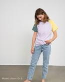 Eine Frau trägt ein fliederfarbenes T-Shirt aus Bio-Baumwolle mit bunten Raglanärmeln der Marke Oktopulli