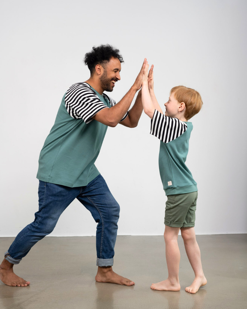 Vater und Sohn klatschen sich in die Hände und tragen dabei das faire Shirt von Oktopulli aus Bio-Baumwolle
