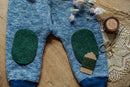 Grüne Wollflicken aus Wollstrick auf Kinderhose, grüne Merinowolle, Storchenschere und Nadelkissen