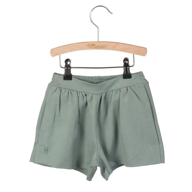 Little Hedonist organic pleated shorts with flowing cut and hidden pockets in Chinois Green. Sustainable fashion for kids.