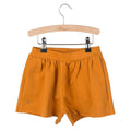 Little Hedonist organic pleated shorts with flowing cut and hidden pockets in Pumpkin Spice. Sustainable fashion for kids.