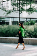 Frau mit grünem Umstandsblazer hält Babybauch