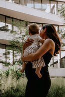 Schwangere Frau im schwarzen Umstandskleid mit Baby im Arm